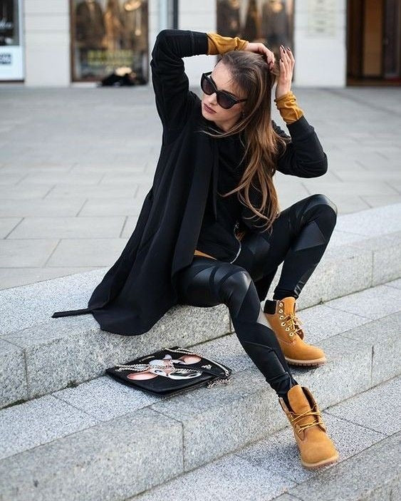 Woman in black outfit with yellow boots sitting on steps outdoors